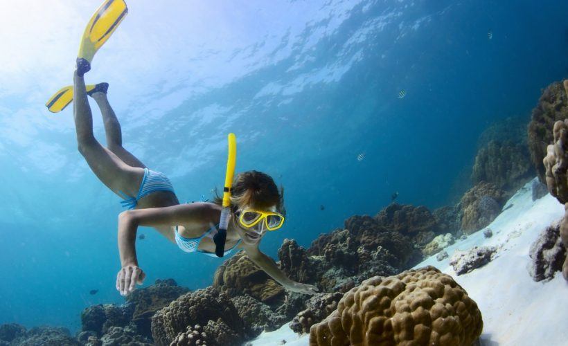 Young lady snorkeling in a tropical sea with yellow fins